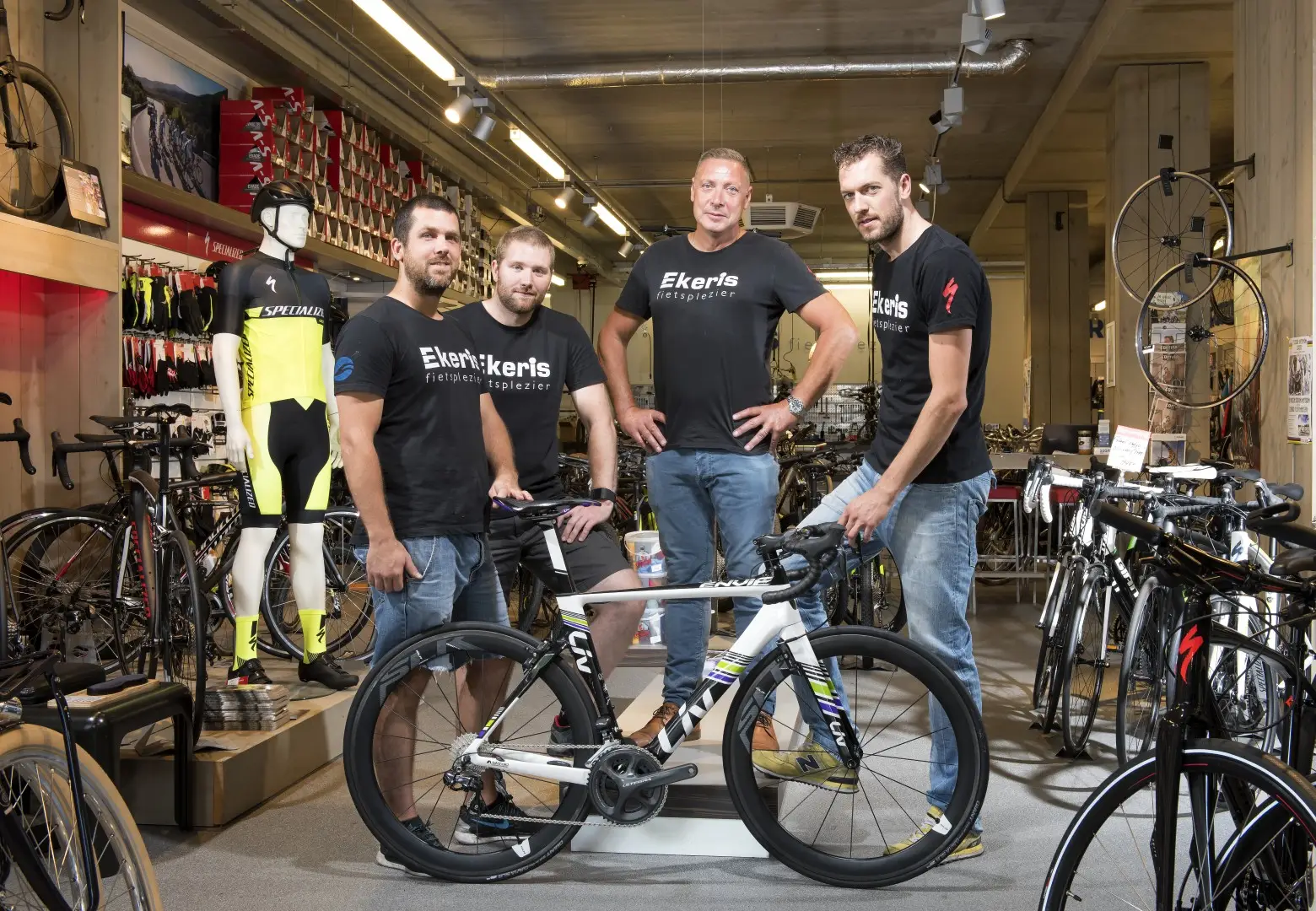 Het team van een fietsenwinkel tussen de racefietsen